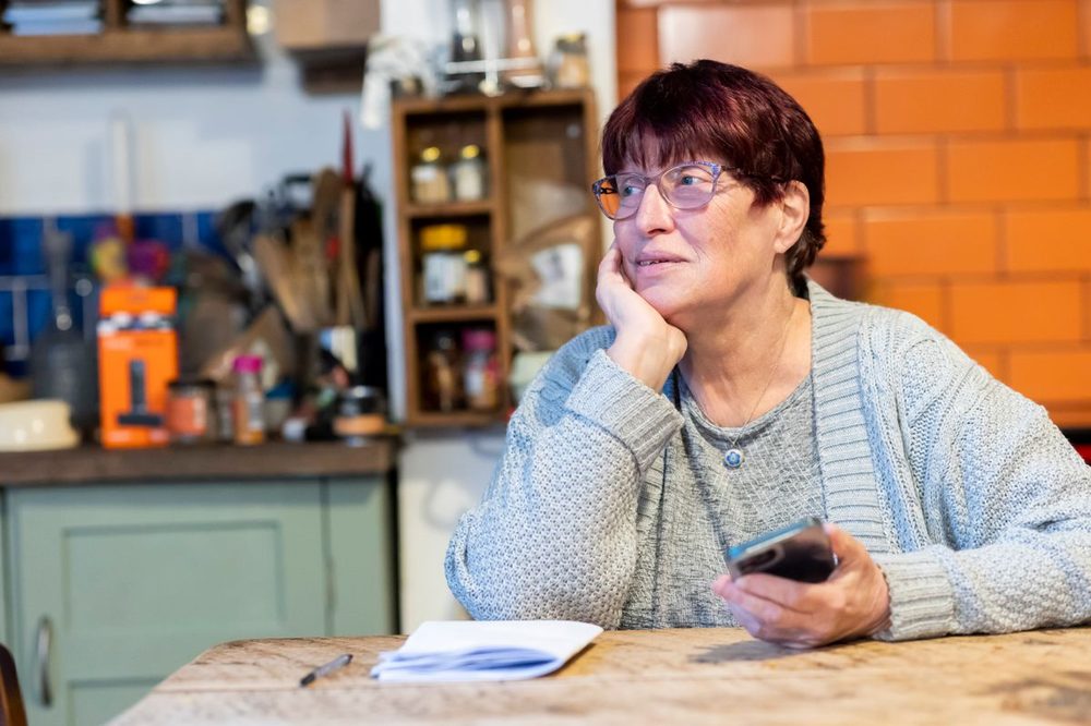 Senior woman checking a message on her phone in her kitchen