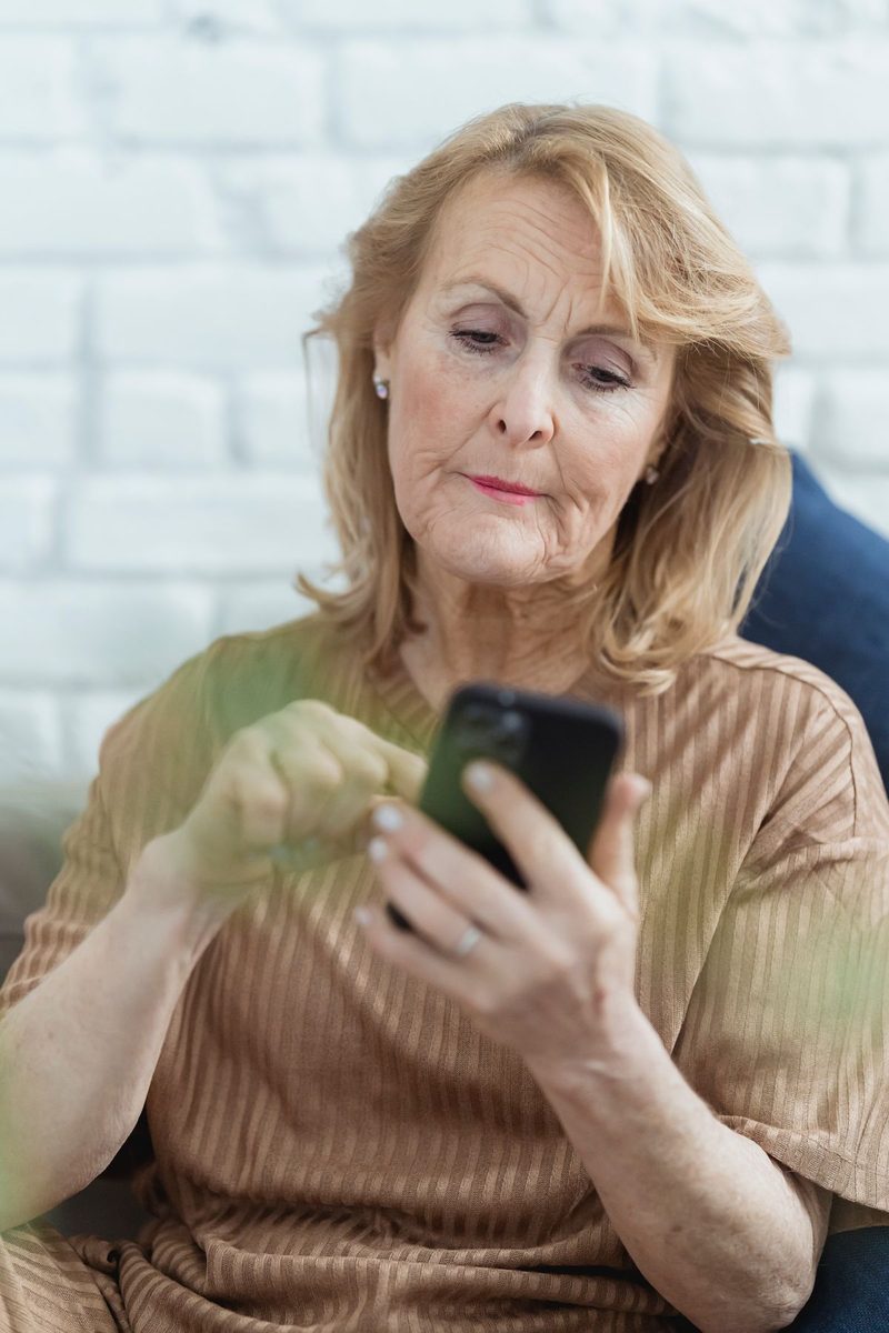 Senior woman reading a text message carefully on her smartphone