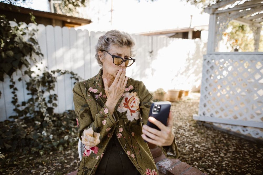 Senior woman smiling during a video call on her smartphone in a garden