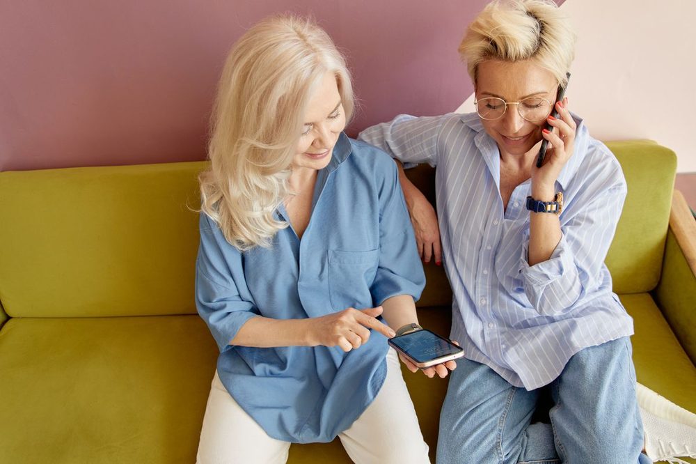 Two senior women looking at a text message together on a smartphone